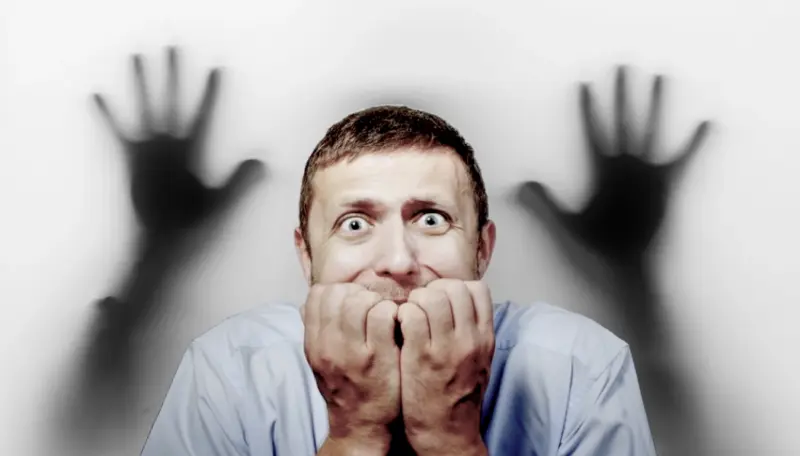 картинка на тему "страх": изображён испуганный мужчина и две тени рук, тянущиеся к нему