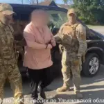 на фото Илья Журавлёв из Инзы в наручниках, его ведут два сотрудника ФСБ с закрытыми лицами.