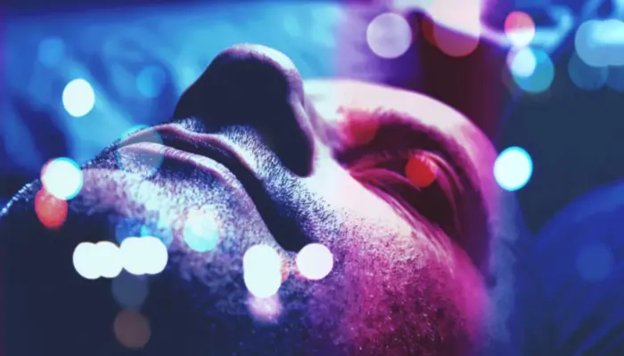 лицо спящего мужчины в сине-лиловом свете