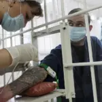 медсестра ерез решётку берёт кровь у заключённого