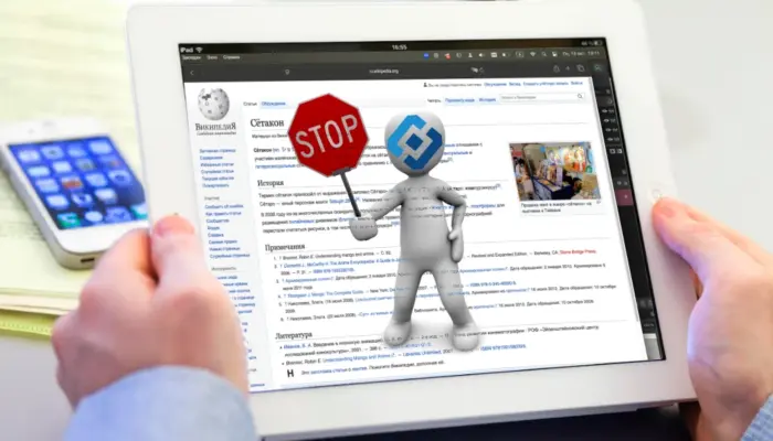 Монитор планшета с открытой страницей Википедии "Сётакон", поверх которой рисованный человечек с логотипом Роскомнадзора на голове показывает знак "СТОП"