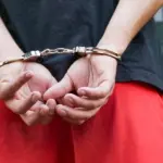 подросток в наручниках с руками за спиной