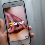 Телефон с открытым Grindr в руке
