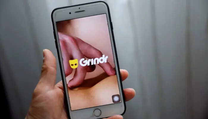 Телефон с открытым Grindr в руке