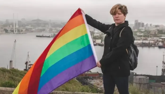 Дальневосточная ЛГБТ-активистка Регина Дзугкоева с прайд-флагом в руках на фоне порта