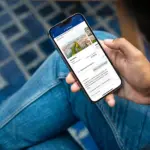 Человек держит в руках смартфон с открытым сайтом Booking.com