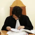 Судья изучает дело, сидя за столом