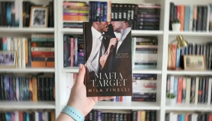 Книга Милы Финелли «Цель мафии» на английском на фоне книжной полки